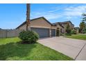 A single story home is shown featuring a three car garage and well maintained lawn and landscaping at 1512 Banner Elk St, Valrico, FL 33594