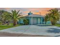 Charming waterfront home featuring a light-blue exterior, lush palm trees, and a spacious driveway at 3181 Gulf Winds Cir, Hernando Beach, FL 34607