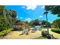 Community pool area with outdoor tables, lush tropical landscaping, and a gazebo at 3907 Orchard Hill Cir, Palm Harbor, FL 34684