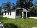 The house features a clean white facade and a well-maintained lawn, complemented by lush trees in the background at 4241 E Palifox St, Tampa, FL 33610
