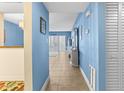 Hallway with beach decor, neutral tile, and blue walls leading to the living space at 4900 Brittany S Dr # 209, St Petersburg, FL 33715