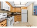 Well-lit kitchen featuring wooden cabinets, white appliances, and granite countertops at 4900 Brittany S Dr # 209, St Petersburg, FL 33715