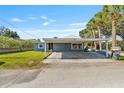 Single-story home featuring a convenient covered carport, manicured lawn and tropical trees at 6726 Udell Ln, Hudson, FL 34667