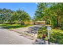 Inviting single-story home with lush landscaping and a concrete driveway leading to a covered carport at 810 W River Dr, Temple Terrace, FL 33617