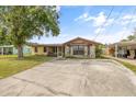 Inviting one-story home with stone accents, a metal roof, mature trees, and a spacious driveway at 9221 W Robson St, Tampa, FL 33615