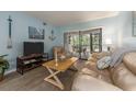 Relaxing living room with coastal decor, light wood floors, and a sliding glass door to the lanai at 105 Woodlake Wynde, Oldsmar, FL 34677