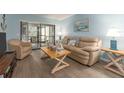Comfortable living room with neutral-toned furniture, wood-look floors, and access to an outdoor patio at 105 Woodlake Wynde, Oldsmar, FL 34677