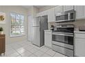 Bright kitchen with stainless steel appliances, white cabinetry, and tiled flooring for a clean and modern look at 1118 Kennewick Ct, Wesley Chapel, FL 33543