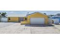 Yellow home featuring a metal roof, solar panels, and a white garage door with concrete driveway at 1421 Sea Gull S Dr, St Petersburg, FL 33707