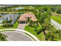 Aerial view of a well-manicured home, complete with a three-car garage, lush landscaping, and tiled roof at 15303 Valencia Del Sol St, Wimauma, FL 33598