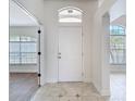 Bright foyer featuring tile flooring and an arched transom window above the white front door at 19910 Wyndmill Cir, Odessa, FL 33556