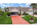 Inviting single-story home with a red driveway, complemented by lush landscaping and a well-maintained lawn at 2015 W Del Webb Blvd, Sun City Center, FL 33573