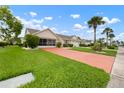 Beautiful single-story home with a well-manicured lawn, tidy landscaping, and a bright red driveway at 2015 W Del Webb Blvd, Sun City Center, FL 33573