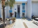 Condo exterior with blue accents, a well-maintained walkway, palm trees, and a grill area for outdoor enjoyment at 230 Medallion Blvd # G, Madeira Beach, FL 33708