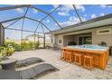 Screened-in lanai with a hot tub, patio furniture, and lush landscaping, perfect for outdoor living at 32231 Conchshell Sail St, Wesley Chapel, FL 33545