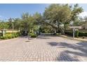 Gated community entrance with mature trees, brick paved street, and manicured landscaping at 502 Creekside Ct, Safety Harbor, FL 34695