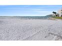 Expansive white sand beach with serene water and a bridge in the background at 830 S Gulfview Blvd # 102, Clearwater Beach, FL 33767