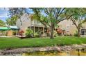 Stunning exterior view featuring a lush lawn, mature tree, balcony, and screened-in patio near the water at 9050 Lake Place Ln, Tampa, FL 33634