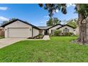 Inviting single-story home with well-manicured lawn, featuring a two-car garage and charming landscaping at 10412 Tara Dr, Riverview, FL 33578