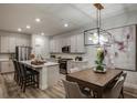 Open-concept kitchen and dining area featuring a modern light fixture and stainless steel appliances at 12172 Cattleside Dr, Riverview, FL 33579