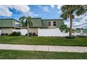 Condo building with a white fence, lush green lawn, palm tree, green roofing and siding, creating a serene atmosphere at 1799 N Highland Ave # 106, Clearwater, FL 33755