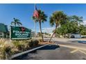 Fountain Square Condominium signage with palm trees, greenery, American flag, and street view showcasing a well-maintained entrance at 1799 N Highland Ave # 106, Clearwater, FL 33755
