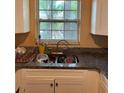 Kitchen sink area with dark countertops, white cabinets, and a window providing natural light at 1806 Marvy Ave, Tampa, FL 33612