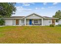 Beautiful single-Gathering home featuring a blue front door, a well-kept lawn, and modern accents at 12106 Meadow Ln, San Antonio, FL 33576