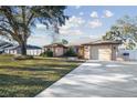 Well-maintained single-story home with a spacious driveway and lush green lawn under a bright sky at 12343 Ascot Ln, Spring Hill, FL 34609