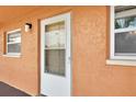 Close-up of a white front door with textured orange siding and a window at 12760 Indian Rocks Rd # 578, Largo, FL 33774