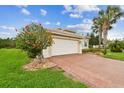 Charming single-story home boasting an attached garage, brick-paved driveway, and blossoming landscaping at 16101 Cape Coral Dr, Wimauma, FL 33598