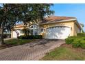 Charming yellow home featuring a brick driveway, a well-kept lawn and manicured landscaping at 4605 Casswell Dr, New Port Richey, FL 34652