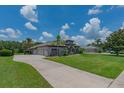Stunning exterior of the house, featuring a large driveway, lush green lawn, and tropical landscaping at 5507 Keeler Oak St, Lithia, FL 33547