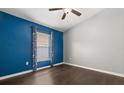 Bright bedroom features wood flooring, ceiling fan, and a blue accent wall at 7606 Nottinghill Sky Dr, Apollo Beach, FL 33572