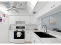 Modern kitchen with white cabinets, marble countertops, sleek black sink, and subway tile backsplash at 9607 Brassie Ct # 9607, New Port Richey, FL 34655