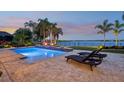 Tranquil pool area with lounge chairs, palm trees, and a scenic lake view at twilight at 11327 Lake Lucaya Dr, Riverview, FL 33579