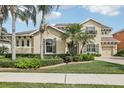 Elegant stucco home with a manicured lawn, lush landscaping, and palm trees at 11327 Lake Lucaya Dr, Riverview, FL 33579