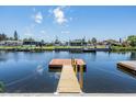 A view of the dock with calm water, houses in the background and a beautiful sky at 13039 Keel Ct, Hudson, FL 34667