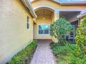 Charming entrance featuring a brick path, lush landscaping, and a covered porch with a pendant light at 16142 Amethyst Key Dr, Wimauma, FL 33598