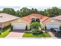 A yellow house with red tile roof, brick driveway, and landscaping in a suburban neighborhood at 16142 Amethyst Key Dr, Wimauma, FL 33598