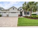 Charming home featuring a three-car garage, well-manicured lawn, and tropical palm trees adding curb appeal at 19608 Lonesome Pine Dr, Land O Lakes, FL 34638