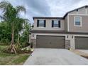 Gorgeous townhome with dark shutters, stone accents, and an attached two-car garage on a cloudy day at 23300 Willow Glen Way, Lutz, FL 33549