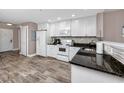 Well-lit kitchen with white cabinets, granite counters, and wood-look tile floor at 399 2Nd St # 217, Indian Rocks Beach, FL 33785