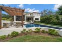 Backyard oasis featuring a sparkling pool, a pergola covered lounge area, and lush landscaping for ultimate relaxation at 419 S Shore Crest Dr, Tampa, FL 33609
