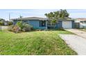 Charming blue home featuring a well-manicured lawn, mature plants, and a single-car garage at 4238 Glissade Dr, New Port Richey, FL 34652