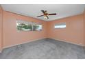 Neutral bedroom featuring carpeted floors, a ceiling fan, and natural light at 7020 Sonata Dr, Port Richey, FL 34668