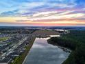 Breathtaking aerial view of a community nestled alongside a scenic lake at sunset at 7819 Notched Pine Bnd, Wesley Chapel, FL 33545