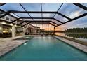 Beautiful screened-in pool area with spa overlooking a tranquil lake at sunset at 7819 Notched Pine Bnd, Wesley Chapel, FL 33545