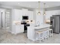 Modern kitchen featuring stainless steel appliances, white cabinets, quartz countertops, and a stylish island with bar stools at 12313 49Th E St, Parrish, FL 34219