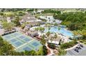 Aerial view of community pool, tennis courts, and surrounding amenities including lush landscaping and golf cart parking at 1530 Ingram Dr # 1530, Sun City Center, FL 33573